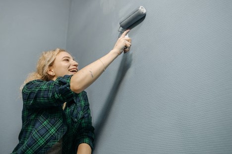 A woman using a roller to repaint your home’s interior